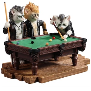 May include: Three anthropomorphic cats playing pool on a green felt table with brown wooden legs. The cats are wearing leather jackets and have human-like features. The table is set up on a wooden platform.