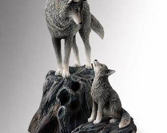 May include: A detailed figurine of two wolves. One wolf stands atop a weathered, dark gray tree stump, while the other sits below, looking up. The wolves are gray with white accents, showcasing a realistic texture.