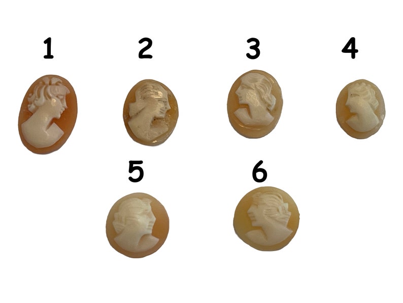 May include: Six cameo pendants with a carved profile of a woman's face. The pendants are oval shaped and have a light brown background with a white cameo.