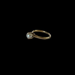 May include: A gold ring with a single pearl set in the center.