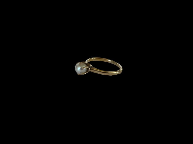 May include: A gold ring with a single pearl set in the center.