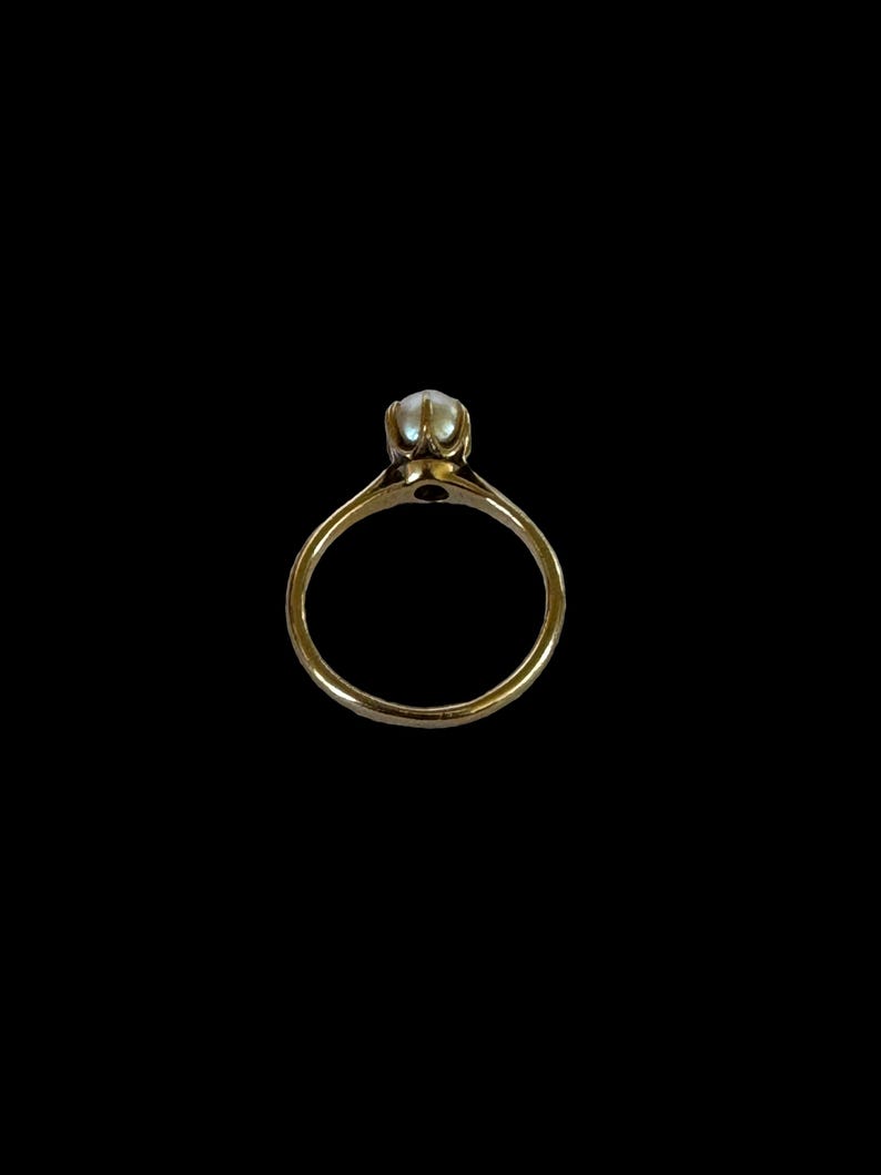 May include: A gold ring with a single pearl set in the center.