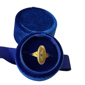 Peut inclure: Une bague en or avec un saphir bleu et des diamants blancs sertis dans une forme ovale. La bague est pr&eacute;sent&eacute;e dans un &eacute;crin &agrave; bague en velours bleu.