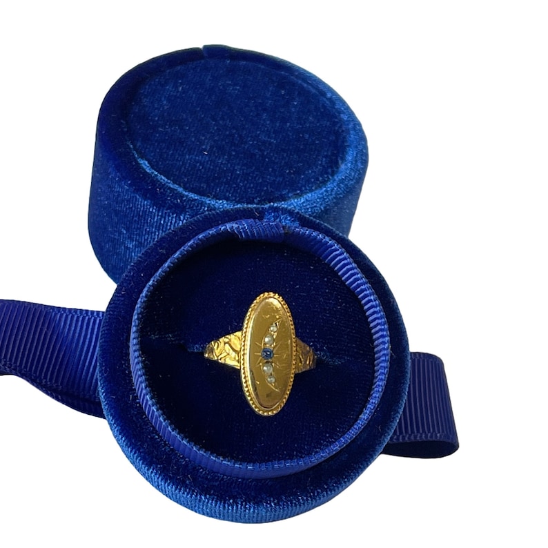 Peut inclure: Une bague en or avec un saphir bleu et des diamants blancs sertis dans une forme ovale. La bague est pr&eacute;sent&eacute;e dans un &eacute;crin &agrave; bague en velours bleu.