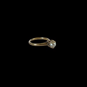 May include: A gold ring with a single pearl set in the center.