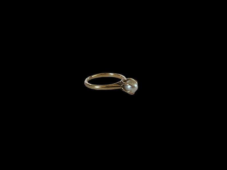 May include: A gold ring with a single pearl set in the center.