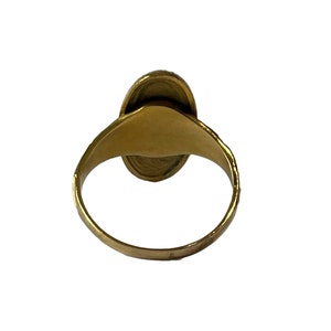 Peut inclure: Une bague en or avec une pierre de forme ovale sertie au centre. La bague est vue de dos, la pierre n'est donc pas visible.