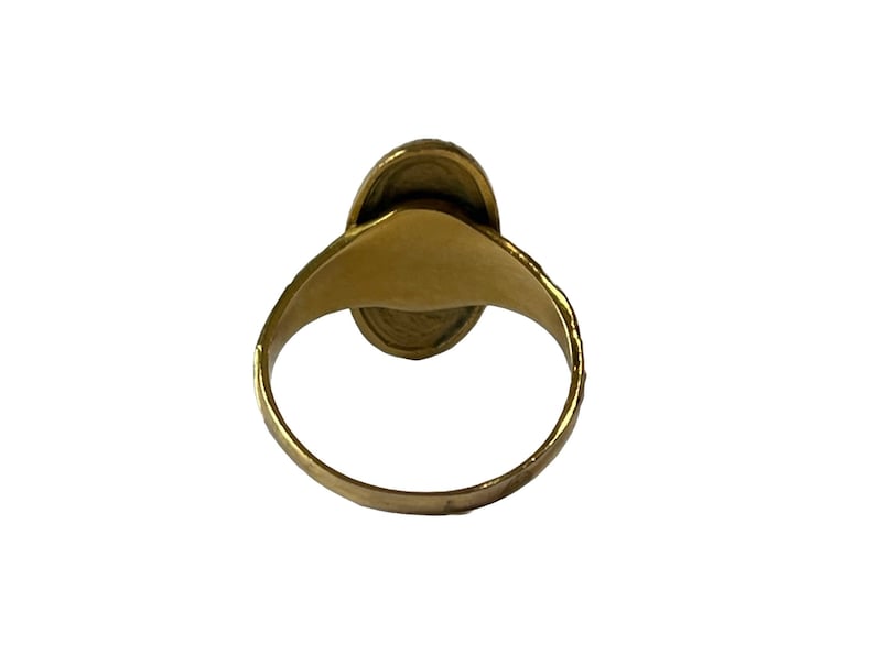 Peut inclure: Une bague en or avec une pierre de forme ovale sertie au centre. La bague est vue de dos, la pierre n'est donc pas visible.