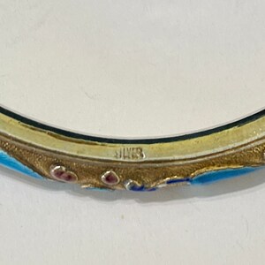 K&ouml;nnte beinhalten: Ein silbernes Armreif-Armband mit blauen und roten Emaildetails. Das Armband ist innen mit "SILVER" gekennzeichnet.