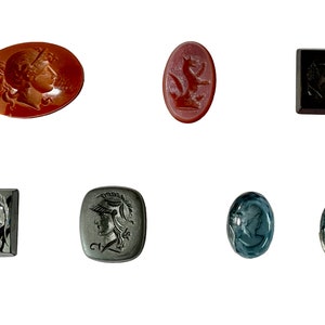 Op de afbeelding: Zes antieke cameo-intagli, waaronder een rode karneol met een vrouwelijk profiel, een rode karneol met een leeuw, een zwarte onyx met een vrouwelijk profiel, een zwarte onyx met een vrouwelijk profiel, een grijze steen met een vrouwelijk profiel en twee blauwe stenen met een vrouwelijk profiel.