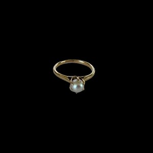 May include: A gold ring with a single white pearl set in the center.