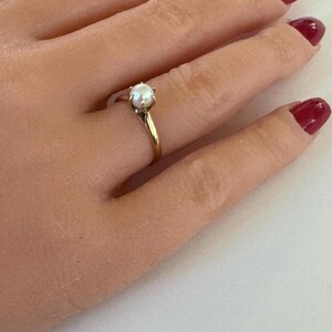 May include: A gold ring with a single white pearl set in a prong setting.