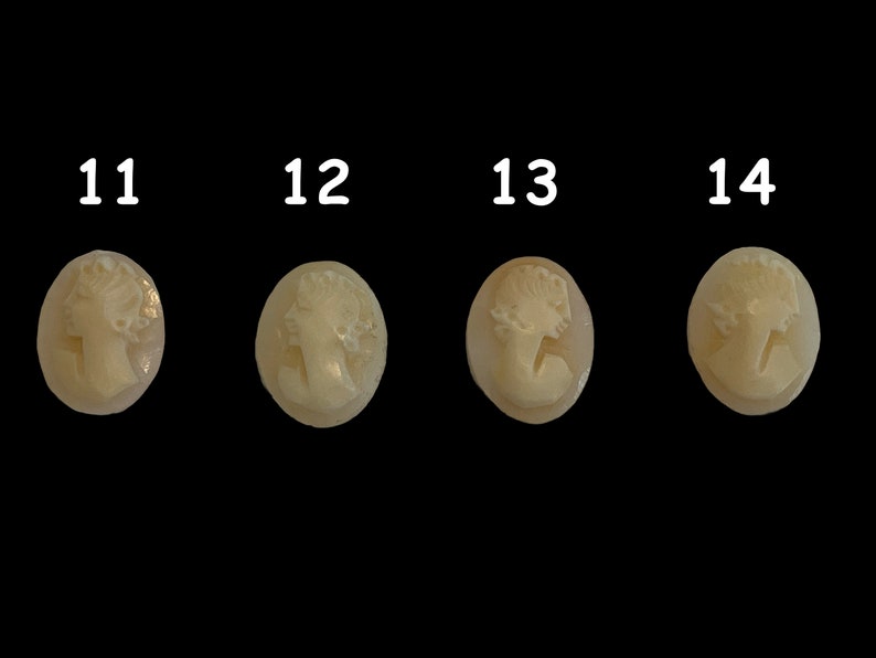 May include: Four white cameo pendants with a carved image of a woman's profile. The pendants are oval shaped and have a smooth, polished surface.