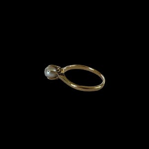 May include: A gold ring with a single pearl set in the center.