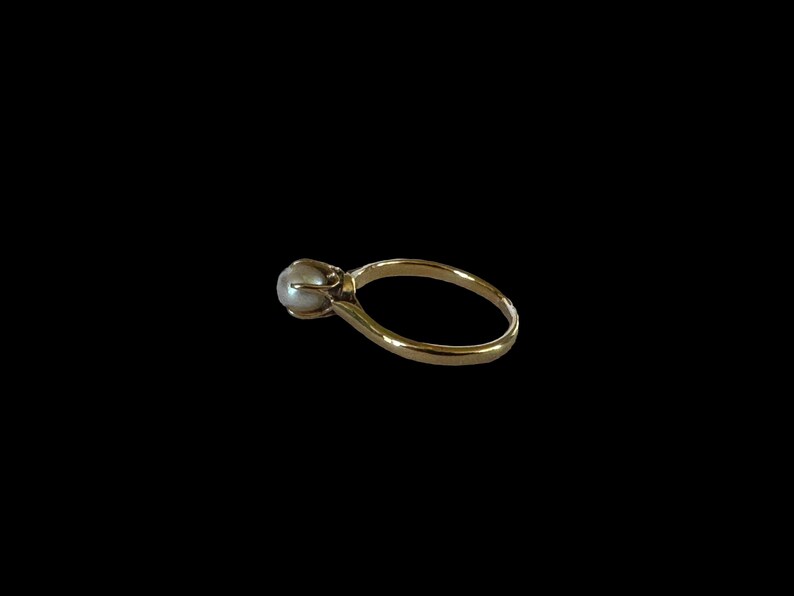 May include: A gold ring with a single pearl set in the center.