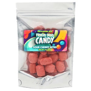 Può includere: Un sacchetto argentato richiudibile pieno di bocconcini di ciliegia acida liofilizzata rosa. Il sacchetto ha un'etichetta che recita "Fun Flavors Box Freeze Dried Candy Sour Cherry Bites Net Wt. 2oz (56g)"