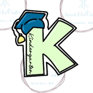 May include: A light green cookie cutter in the shape of the letter "K" with a graduation cap and the word "Kindergarten" in black. The graduation cap is blue with a yellow tassel. The cutter has a black outline.