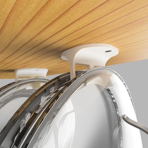 May include: A modern, white kitchen appliance with a curved, transparent design. The appliance is mounted on a wooden surface and features a metallic handle. The design is sleek and contemporary, suggesting a focus on functionality and style.