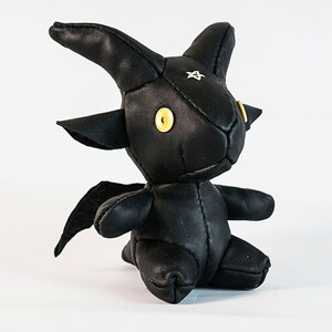 May include: Black leather stuffed toy shaped like a goat with yellow eyes and a star on its forehead.