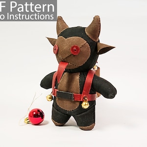 May include: A brown and black plush toy with red horns and a red tongue. The toy is wearing a red leather harness with a black belt and gold bells. The toy is standing on a white surface with a red Christmas ornament.