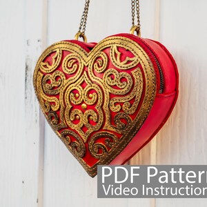 May include: A red heart-shaped leather bag with gold filigree detailing and a chain strap. The bag has a zipper closure. PDF Pattern Video Instructions.