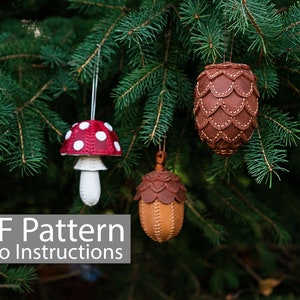 May include: Three leather Christmas decorations hanging on a pine tree branch. The decorations are a red and white mushroom, a brown acorn, and a brown pine cone. The text "PDF Pattern Video Instructions" is at the bottom of the image.