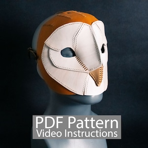 Puede incluir: Una máscara de búho de cuero blanco y marrón con detalles cosidos. La máscara está en una cabeza de maniquí gris. El texto "PDF Pattern Video Instructions" está debajo de la máscara.