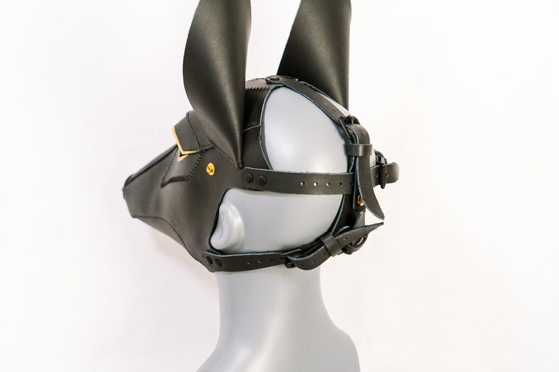 May include: Black leather mask with gold accents and adjustable straps. The mask has two large ears and a snout.