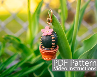 Peut inclure: Un porte-clés en cuir vert en forme de cactus avec une fleur rose et un pot en cuir marron.  Modèle PDF Instructions vidéo.