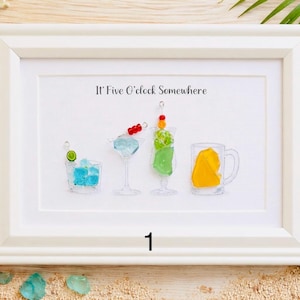 May include: White framed art print featuring four colorful cocktail illustrations. The text "It's Five O'clock Somewhere" is above the drinks. The artwork includes a blue drink with ice, a martini, a green drink, and a yellow drink in a mug.