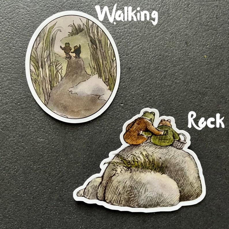 Puede incluir: Dos pegatinas de ranas, una con dos ranas caminando por un sendero a trav&eacute;s de hierba alta y la otra con dos ranas sentadas en una gran roca.