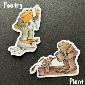 Puede incluir: Dos pegatinas de ranas, una leyendo un libro titulado "Poemas" y la otra regando una planta. Las pegatinas est&aacute;n sobre un fondo gris oscuro. El texto "Poes&iacute;a" est&aacute; sobre la primera rana y el texto "Planta" est&aacute; debajo de la segunda rana.
