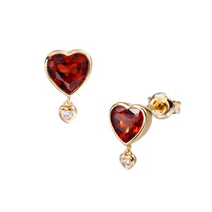 May include: A pair of gold heart-shaped earrings with red gemstone accents and a smaller diamond heart dangling from each earring.
