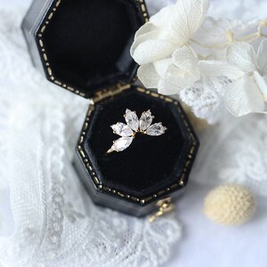 Puede incluir: Un anillo de oro con una montura de diamante en forma de marquesa. El anillo est&aacute; en una caja de anillo de terciopelo negro.