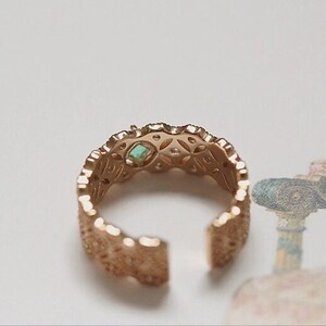 May include: Gold ring with a delicate, intricate design. The ring features a small turquoise gemstone in the center.