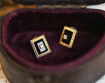 May include: A pair of gold cufflinks with black onyx and a small diamond in the center. The cufflinks are in a velvet-lined box.