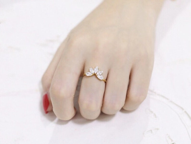 Puede incluir: Un anillo de oro con un grupo de piedras claras en forma de marquesa engastadas en una banda delicada.