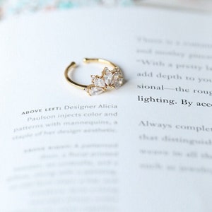Puede incluir: Un anillo de oro con un grupo de piedras de circonita c&uacute;bica transparentes en un dise&ntilde;o con forma de hoja.