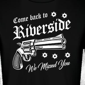 Puede incluir: Camiseta negra con un gráfico blanco de un revólver y el texto "Come back to Riverside We Missed You".
