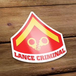 May include: A red and yellow sticker with a military rank insignia and the text "Lance Criminal".