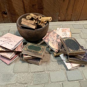以下が含まれることがあります： ミニチュアの本と巻かれた紙のスクロールのコレクション。一部の本は緑と金の装飾的な表紙で、他の本は手書き風のテキストが書かれたヴィンテージスタイルの紙の表紙です。暗い茶色の木製のボウルには、いくつかの巻かれた紙のスクロールが入っています。