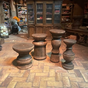 Puede incluir: Cuatro pedestales de madera de diferentes tamaños y estilos. Los pedestales son de madera marrón oscura y tienen un acabado desgastado. Están dispuestos en un suelo de baldosas.