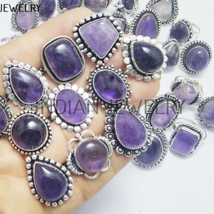 May include: A collection of amethyst gemstone rings with silver settings. The rings feature various styles, including round, oval, and teardrop shapes.