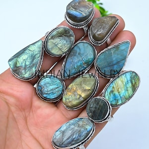May include: A collection of silver rings with iridescent labradorite stones. The rings feature various shapes, including oval, teardrop, and round designs. The text "INDIAN JEWELRY" is visible at the top.