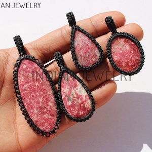 May include: Four pink and white gemstone pendants with black macrame cord. The pendants are in various shapes and sizes.