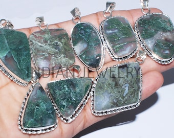 May include: Collection of moss agate pendants in various shapes, including rectangular, oval, and triangular. Each pendant features a unique pattern of green and white within the stone, set in a silver-toned metal frame. The text "INDIAN JEWELRY" is visible at the top.