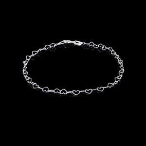 May include: A delicate silver bracelet featuring a repeating heart design. The bracelet is composed of small, open-heart shapes linked together, creating a romantic and elegant accessory. The clasp is visible at the top of the bracelet.