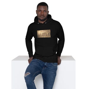 May include: A black hooded sweatshirt featuring a rectangular graphic print on the chest. The print depicts a sepia-toned historical scene of figures in motion, including a prominent menorah. The hoodie has long sleeves and a drawstring hood.