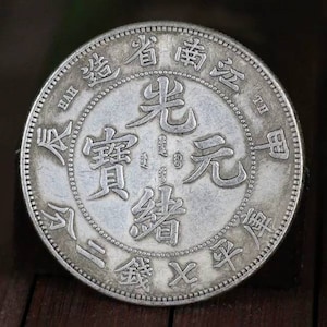 以下が含まれることがあります： 「光緒元寶」 (Guangxu Yuanbao) と「大清銀幣」 (Da Qing Yinbi) の文字が刻まれた銀製の中国の硬貨。コインには、左側に「寶」 (Bao)、右側に「庫」 (Ku) の文字も刻まれています。
