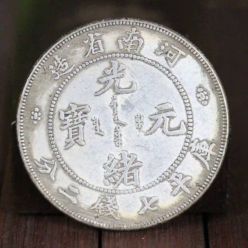 Pode incluir: Uma moeda chinesa de prata com os caracteres "光緒元寶" (Guangxu Yuanbao) e "大清銀幣" (Da Qing Yinbi) inscritos nela. A moeda tamb&eacute;m apresenta um design de drag&atilde;o.